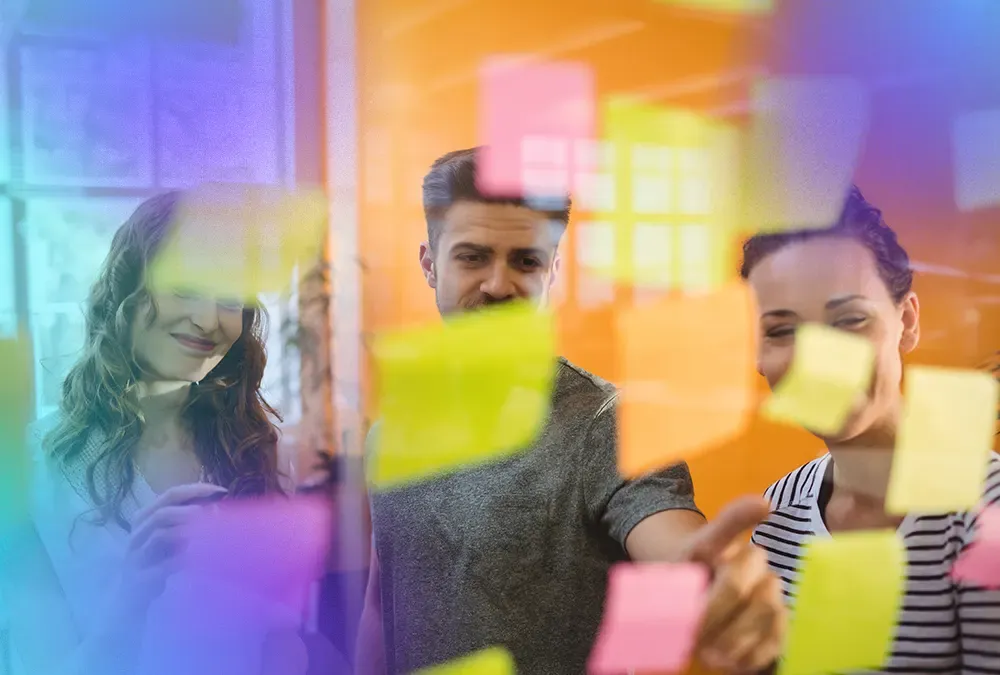 Equipo de Whizz Partners trabajando con post-its en una pared de vidrio